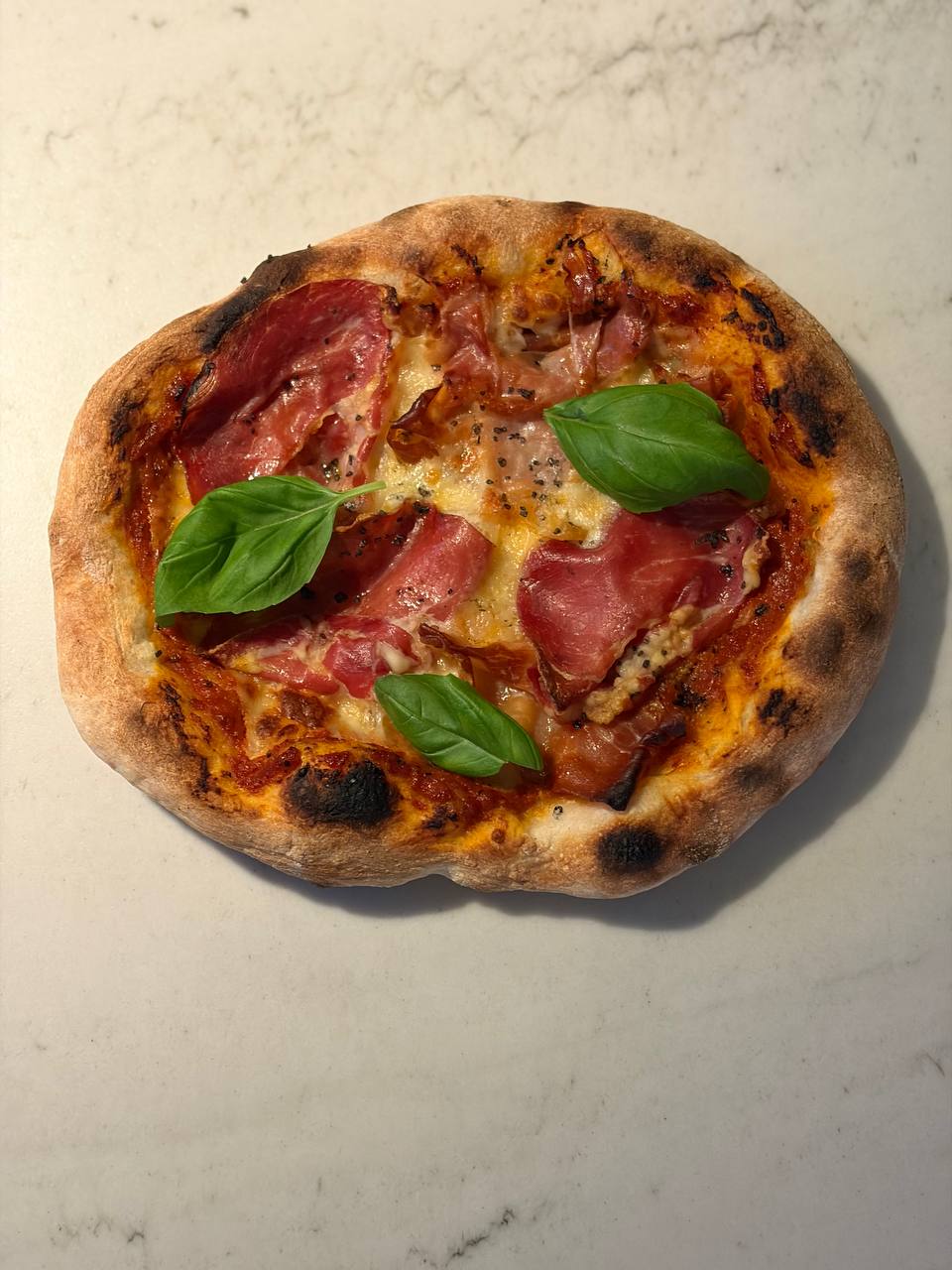 Neapolitanische Pizza mit Prosciutto und Basilikum